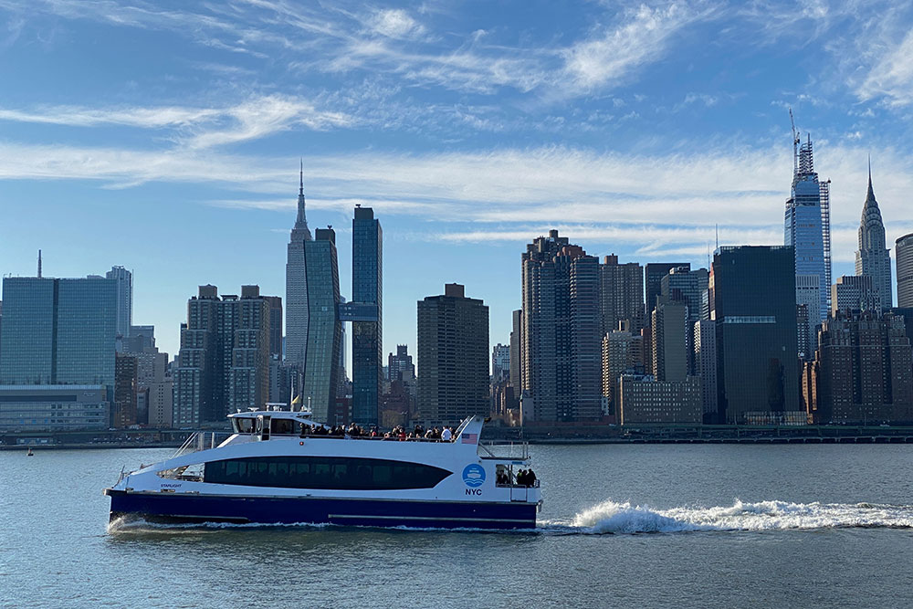 NYC ferry in the east river with Manhattan behind it