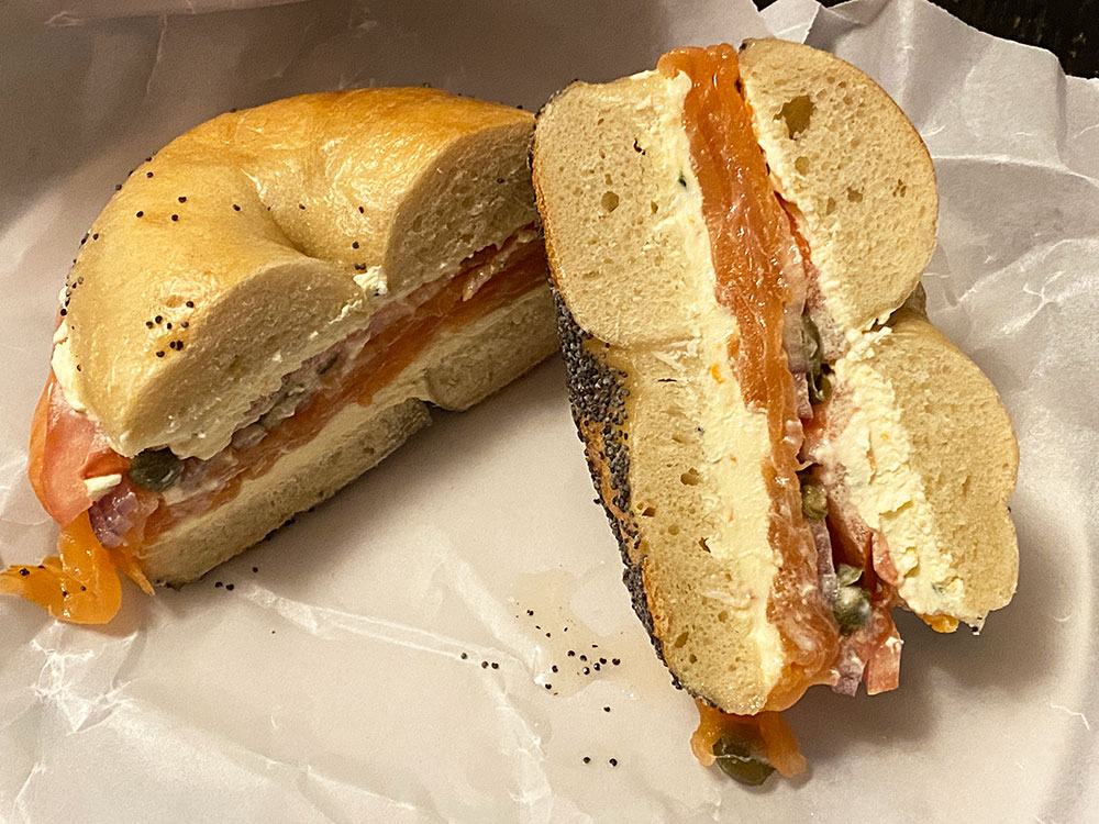A cross section of a poppy seed bagel showing cream cheese, lox, onion, capers from Simply Nova, steps from the Graham Ave L Station
